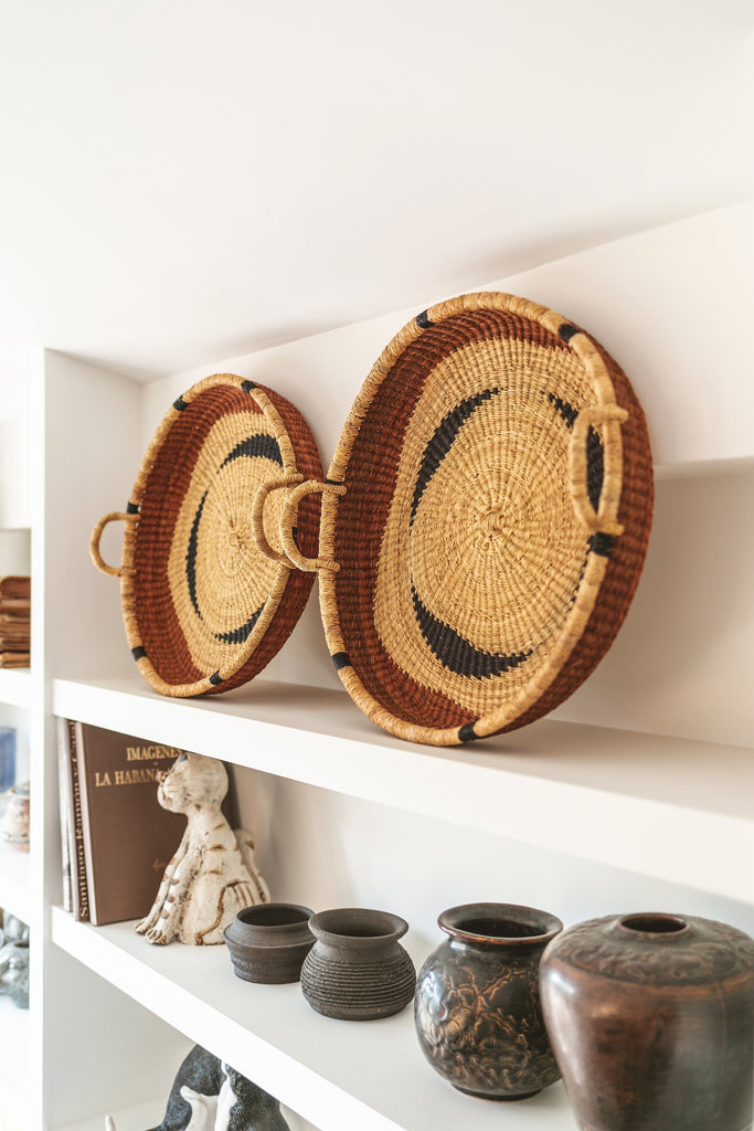 Wall hanging basket on a white shelf.  Round tray baskets with handles.  Designed by Akan Republic.