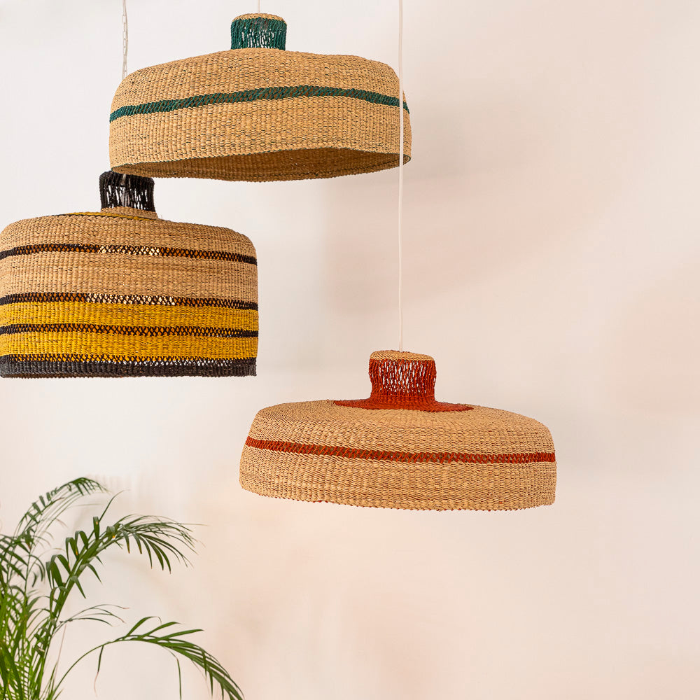 Three hanging lampshades in different colours are arranged closely together. Designed by Akan Republic baskets.